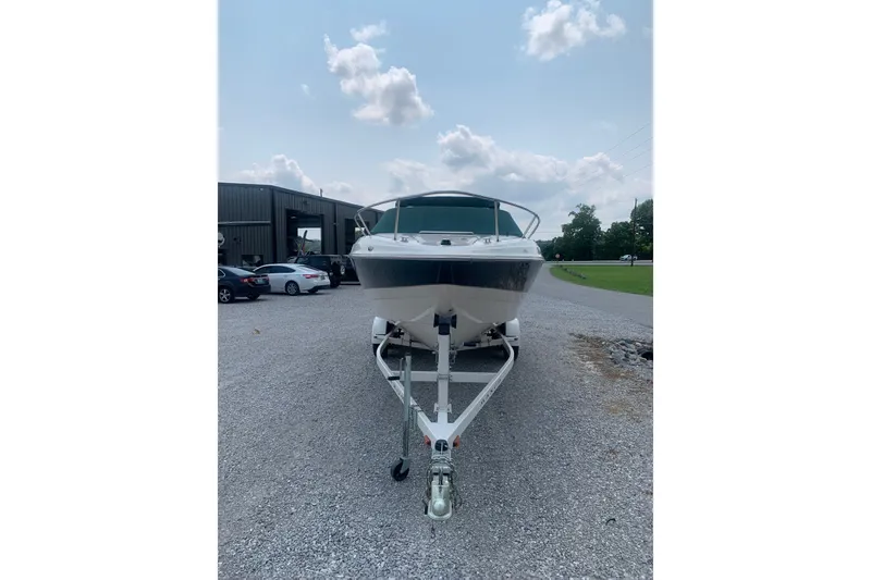 Slide: The Image of 2000 Maxum 2300 SC boat on trailer, parked outdoors under a partly cloudy sky. - 2
