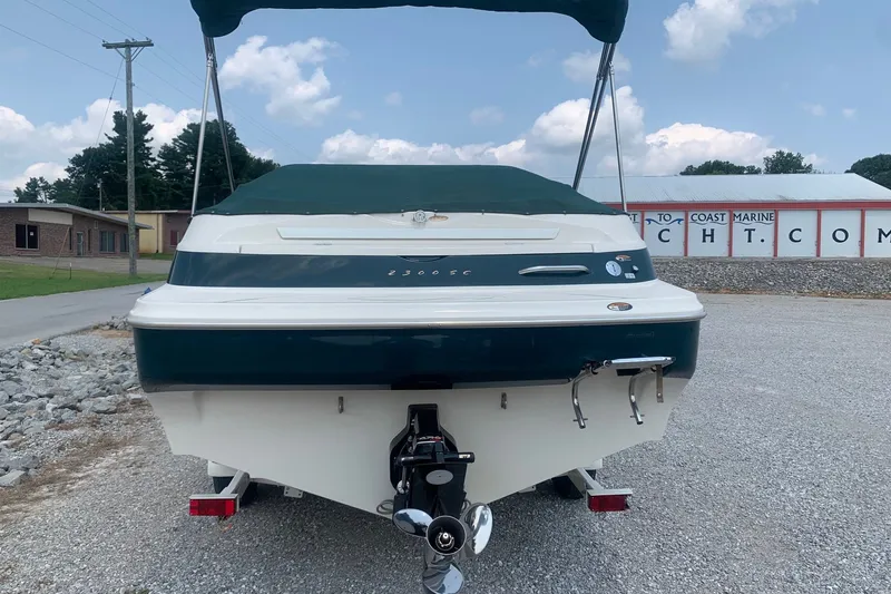Slide: The Image of 2000 Maxum 2300 SC boat with green cover, parked on gravel lot. - 3