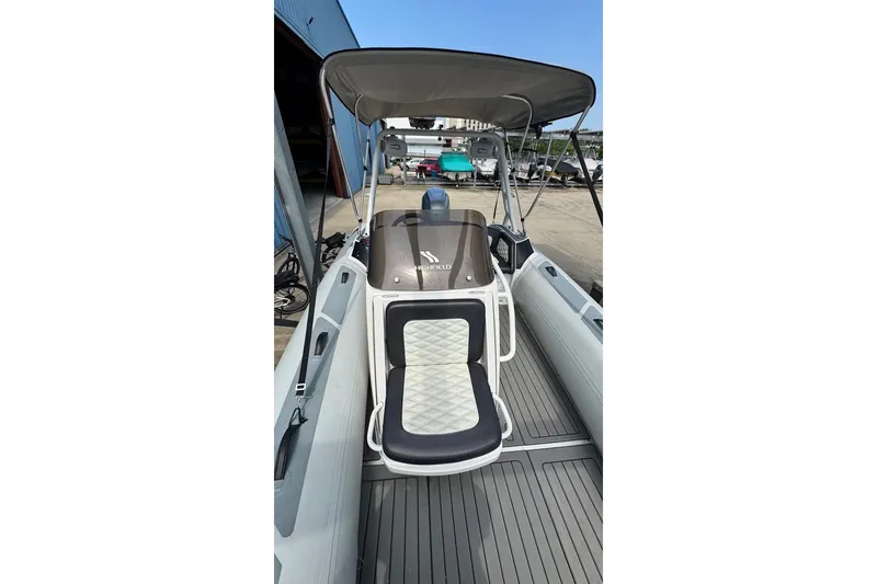 Slide: The Image of 2021 Highfield Sport 520 boat with cushioned seating and canopy, docked outdoors. - 14