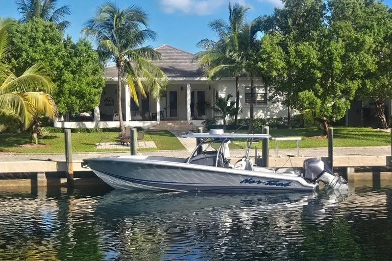 Slide: The Image of 2024 Nor-Tech 340 Sport boat docked by a tropical waterfront home. - 10