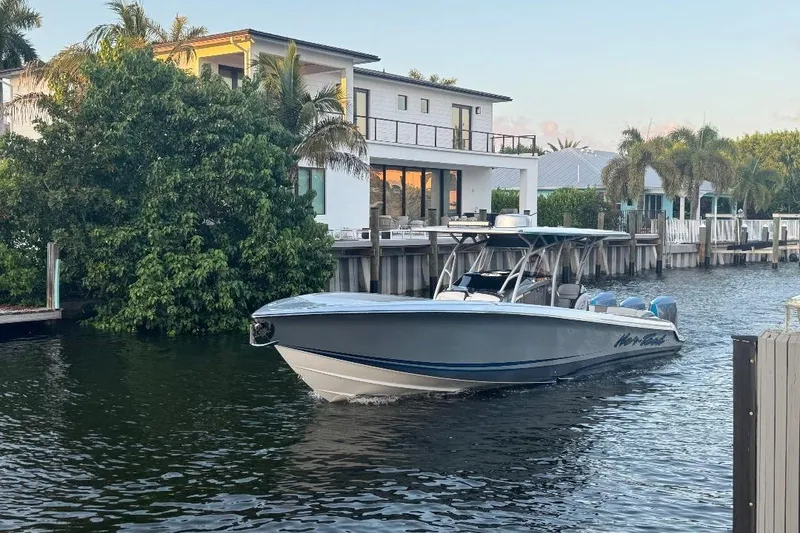 Slide: The Image of 2024 Nor-Tech 340 Sport boat cruising near waterfront homes with lush greenery. - 7