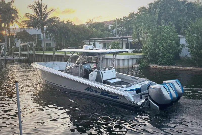 Slide: The Image of 2024 Nor-Tech 340 Sport boat on water at sunset, surrounded by palm trees. - 6