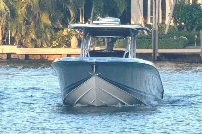 Slide: The Image of 2024 Nor-Tech 340 Sport boat cruising on calm water near a lush shoreline. - 9