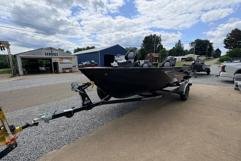 Slide: The Image of A black Crestliner 1650 Kodiak SC boat on a trailer, parked on a gravel lot. - 9