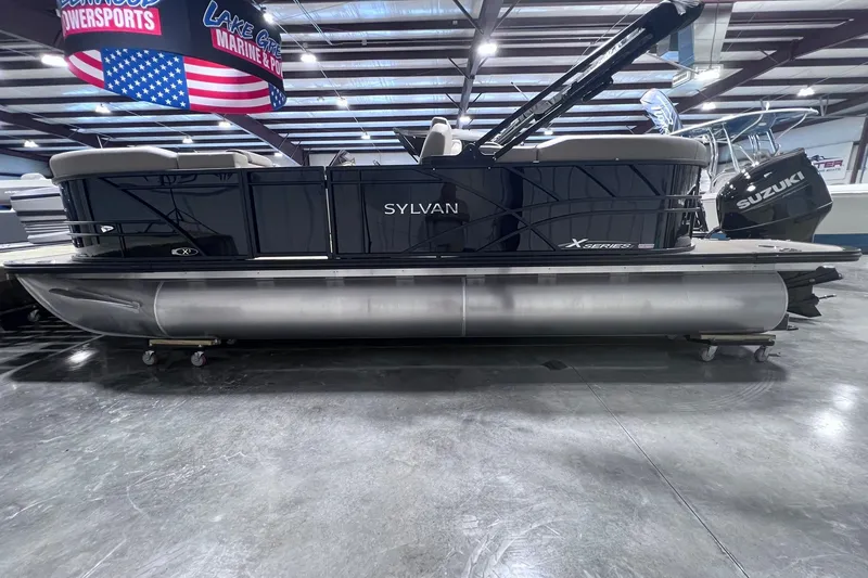The Image of 2026 Sylvan X3 pontoon boat displayed indoors with Suzuki outboard motor. - 1
