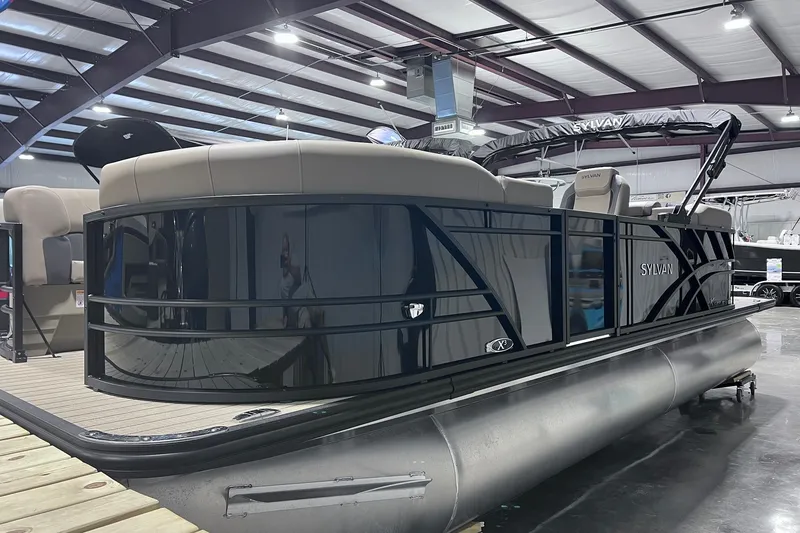 Slide: The Image of 2026 Sylvan X3 pontoon boat in showroom, featuring sleek design and modern seating. - 2