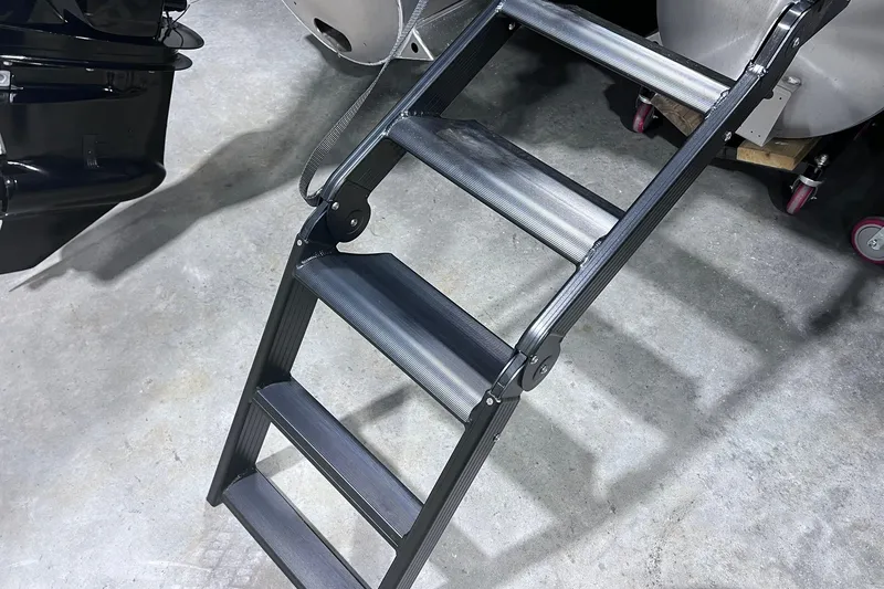 Slide: The Image of Folding ladder on concrete floor, near Sylvan X3 2026 boat components. - 16