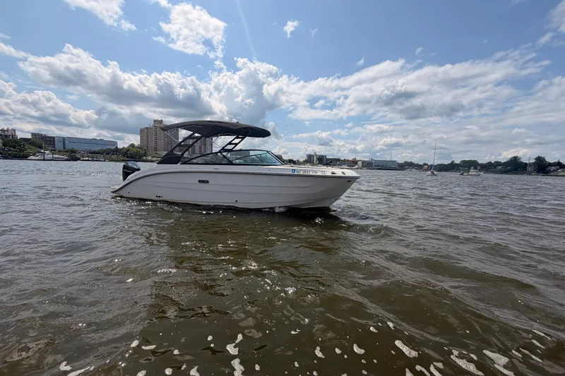 Slide: The Image of 2025 Sea Ray SDX 250 Outboard boat on a sunny day, cityscape background. - 1