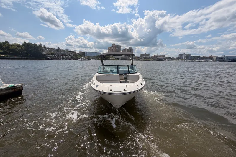 Slide: The Image of 2025 Sea Ray SDX 250 Outboard boat cruising on a sunny day in a city harbor. - 2