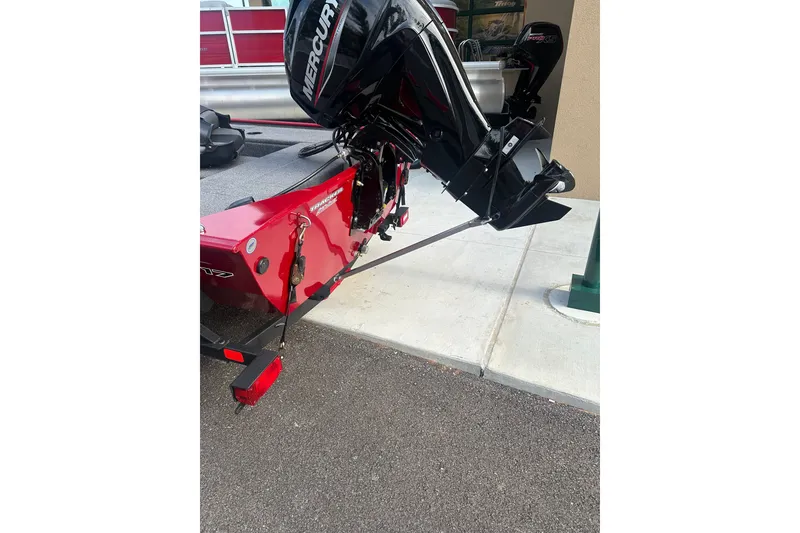 Slide: The Image of Red Grumman Rouge 150 T boat with Mercury outboard motor, parked on pavement. - 5