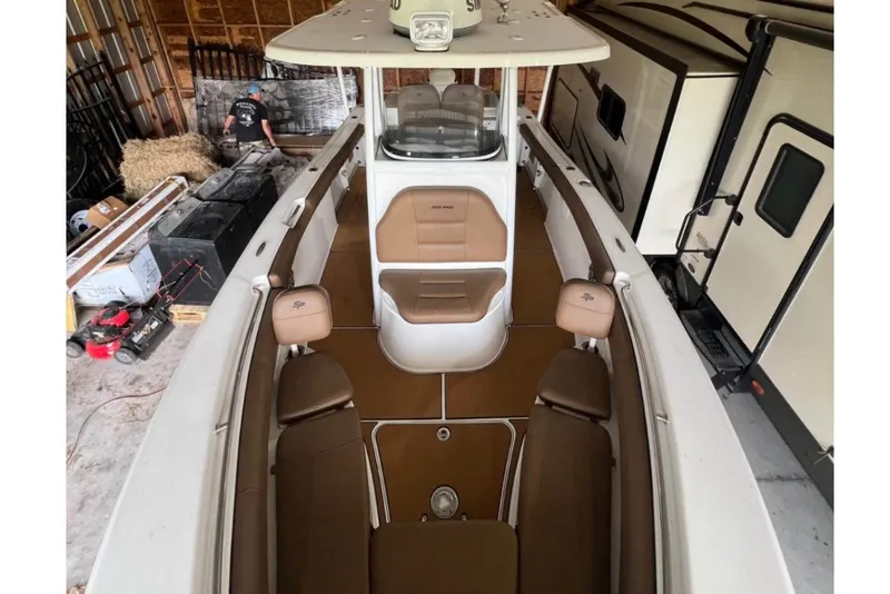 Slide: The Image of 2018 Sea Pro 239 Center Console boat interior in storage, featuring brown seating and white deck. - 2