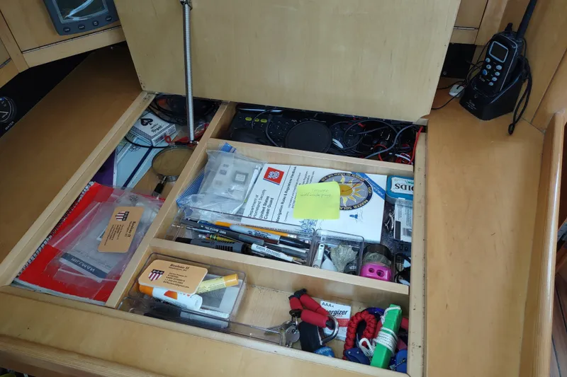 Slide: The Image of Open storage compartment on a 2005 Garcia Passoa 47 yacht, containing various tools and documents. - 81