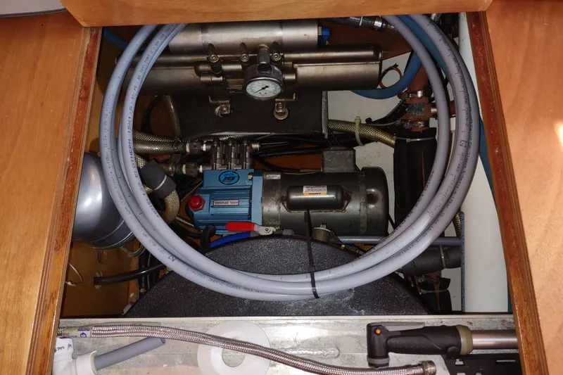 Slide: The Image of Engine compartment of a 2005 Garcia Passoa 47 sailboat, featuring hoses and mechanical components. - 73