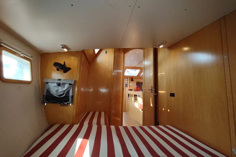 Slide: The Image of Cozy cabin interior of 2005 Garcia Passoa 47 yacht with striped bedding and wooden finish. - 24