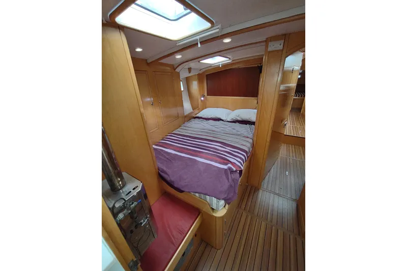 Slide: The Image of Cozy cabin interior of 2005 Garcia Passoa 47 yacht with wooden finish and striped bedding. - 30