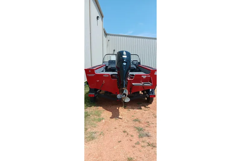 Slide: The Image of Red 2026 Tracker Targa V-18 Combo boat with outboard motor, parked outdoors. - 2