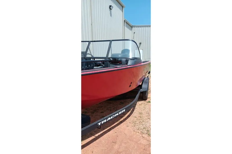 Slide: The Image of 2026 Tracker Targa V-18 Combo boat with red exterior on trailer, parked outdoors. - 17