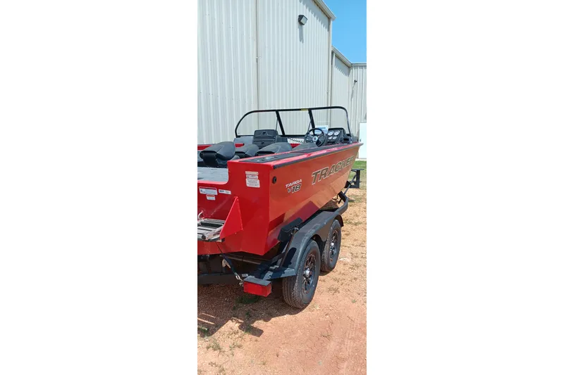 Slide: The Image of Red 2026 Tracker Targa V-18 Combo boat on trailer, parked near a metal building. - 4
