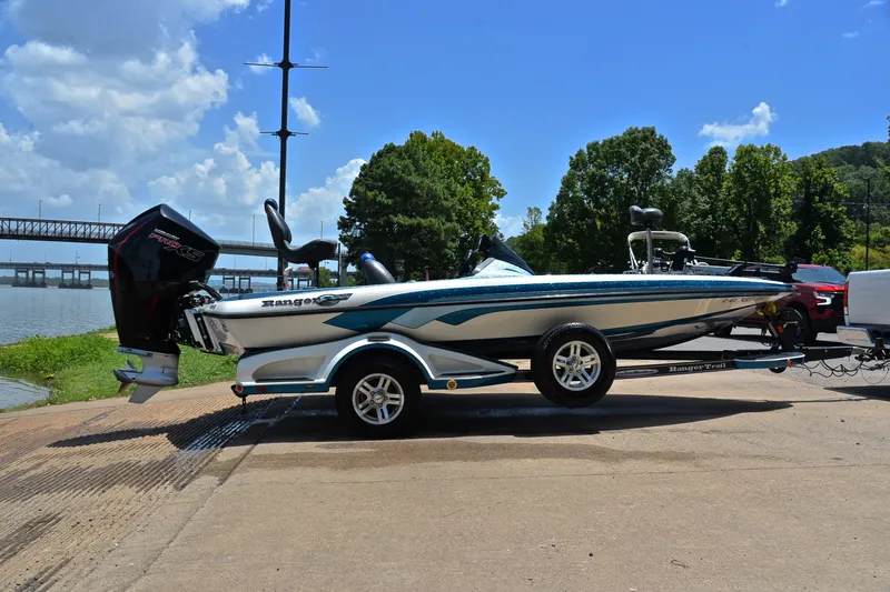 Slide: The Image of 2012 Ranger Z518 boat on trailer by a river, under a clear blue sky. - 15
