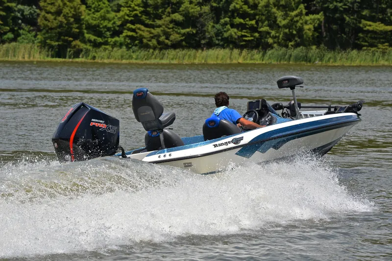 Slide: The Image of 2012 Ranger Z518 boat speeding on a lake with lush green trees in the background. - 5