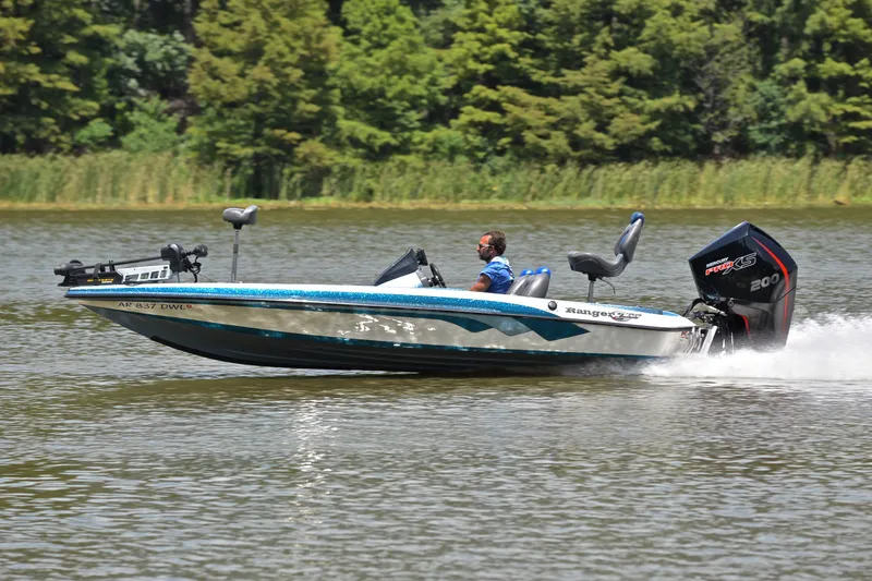 The Image of 2012 Ranger Z518 boat speeding on a lake with lush green trees in the background. - 2