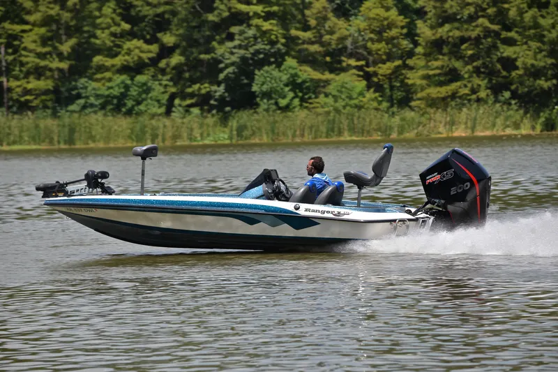 Slide: The Image of 2012 Ranger Z518 boat speeding on a lake with lush green trees in the background. - 4