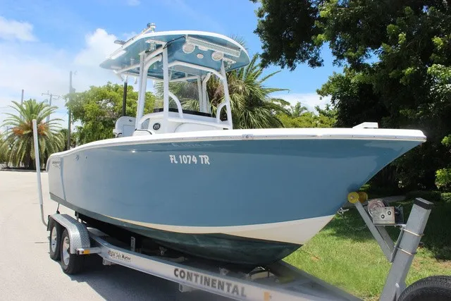The Image of A 2023 Sea Pro 219 Center Console boat on a trailer, surrounded by palm trees and blue sky. - 1