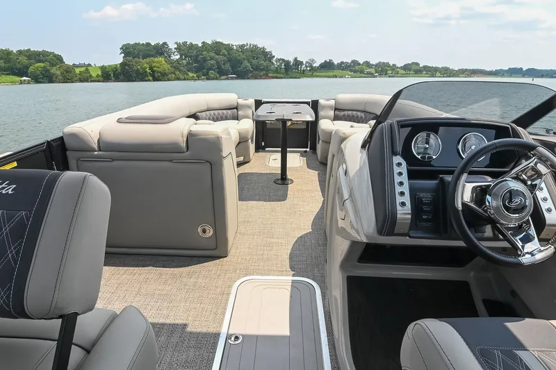 Slide: The Image of 2025 Barletta Lusso 25UCA pontoon boat interior with luxurious seating and modern dashboard on a lake. - 9