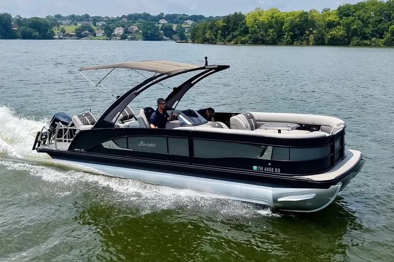 The Image of 2025 Barletta Lusso 25UCA pontoon boat cruising on a scenic lake. - 0