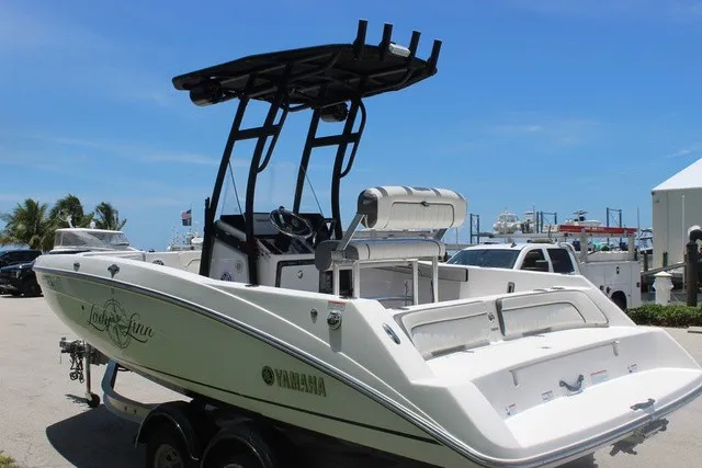 Slide: The Image of A white 2021 Yamaha 210 FSH Sport boat with T-top, parked on a trailer. - 9