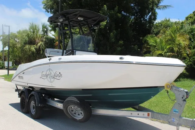 Slide: The Image of A 2021 Yamaha 210 FSH Sport boat on a trailer, surrounded by trees. - 14