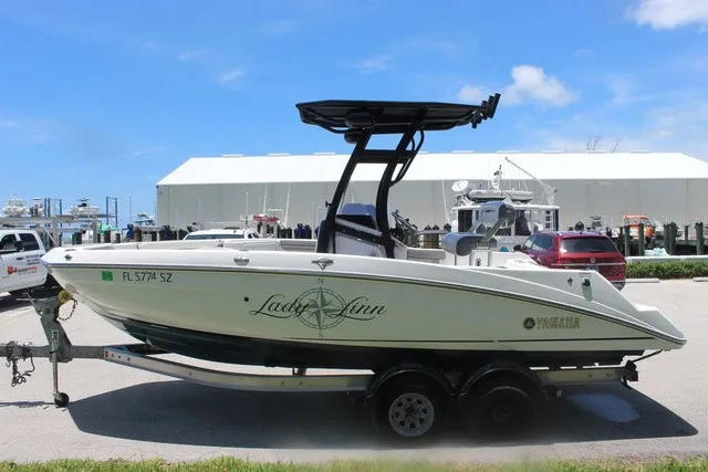 Slide: The Image of A 2021 Yamaha 210 FSH Sport boat on a trailer, featuring a black T-top. - 10