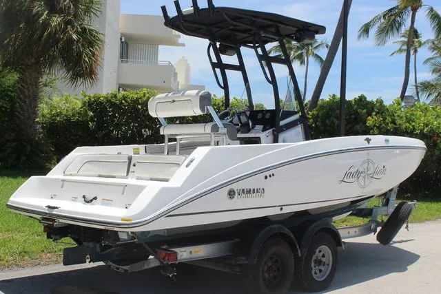 Slide: The Image of A 2021 Yamaha 210 FSH Sport boat on a trailer, surrounded by palm trees. - 4