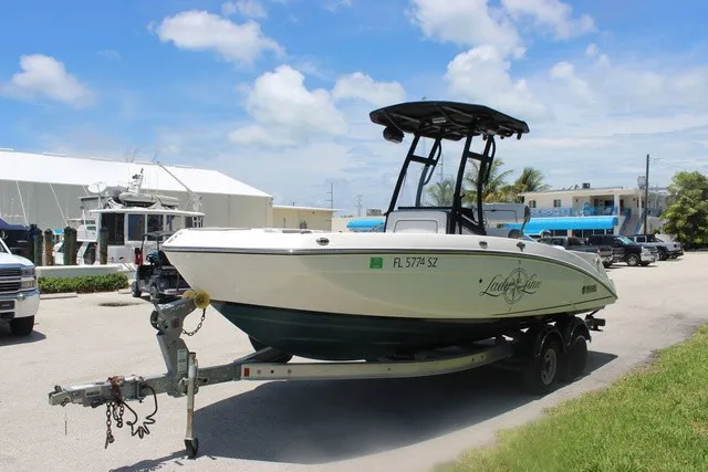 Slide: The Image of A 2021 Yamaha 210 FSH Sport boat on a trailer in a sunny harbor area. - 11