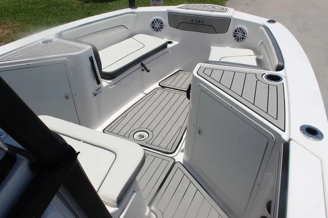 Slide: The Image of The image shows the cockpit of a 2021 Yamaha 210 FSH Sport boat with gray upholstery and speakers. - 28