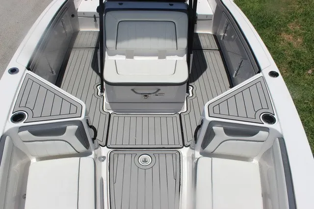 Slide: The Image of The image shows the cockpit of a 2021 Yamaha 210 FSH Sport boat with gray upholstery and storage. - 26