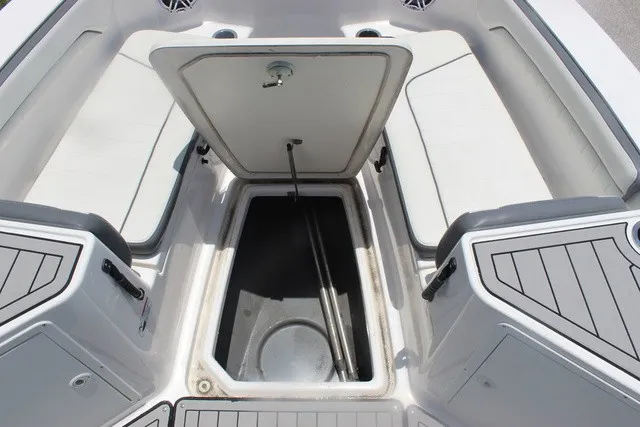Slide: The Image of An open storage compartment on a 2021 Yamaha 210 FSH Sport boat, surrounded by cushioned seating. - 49