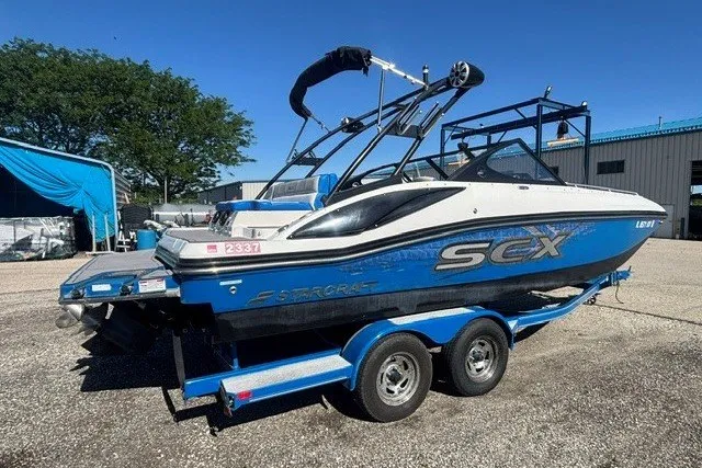 Slide: The Image of 2017 Starcraft SCX Surf 211 IO boat on trailer, blue and white design, parked outdoors. - 30