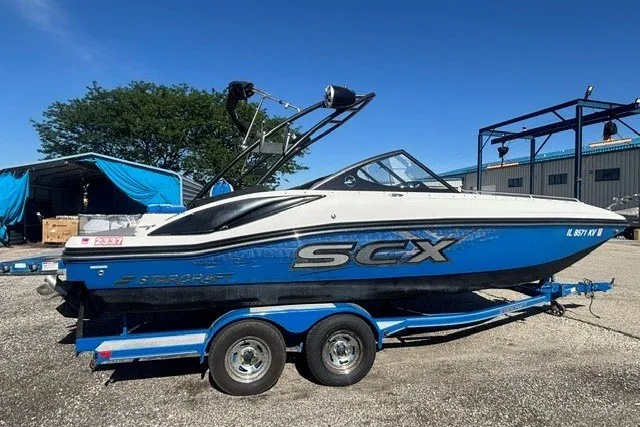 Slide: The Image of 2017 Starcraft SCX Surf 211 IO boat on trailer, blue and white design, parked outdoors. - 31