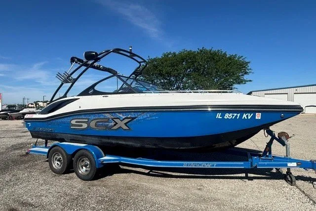 The Image of 2017 Starcraft SCX Surf 211 IO boat on trailer, blue and white design. - 0