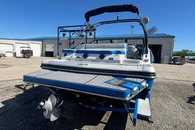 Slide: The Image of 2017 Starcraft SCX Surf 211 IO boat with blue accents, parked outdoors. - 15