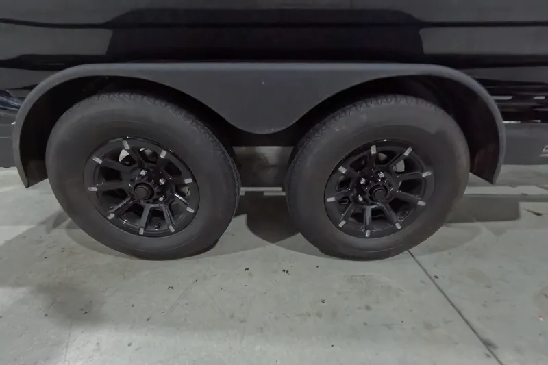 Slide: The Image of 2026 Skeeter ZXR21 SE trailer wheels, black rims, parked indoors. - 3