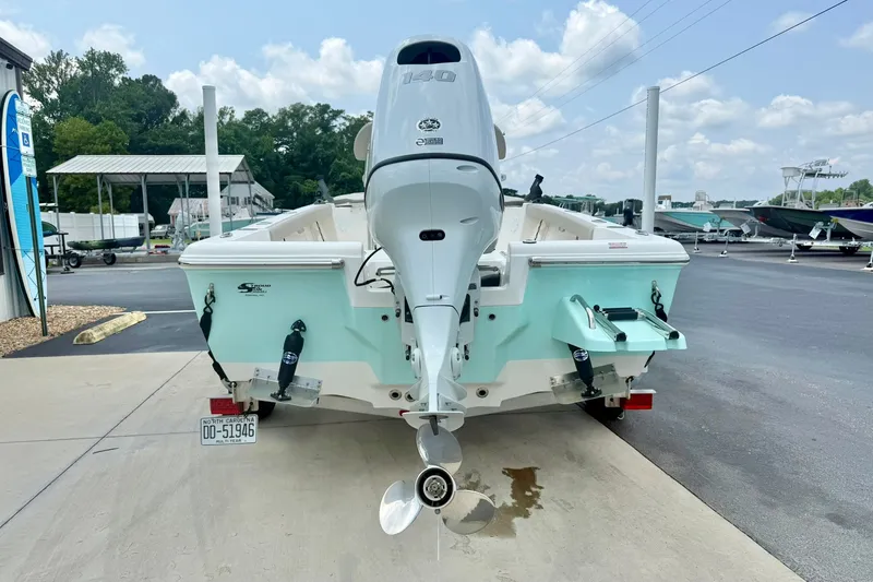 Slide: The Image of 2025 Key West 188 Bay Reef boat with outboard motor, parked on a sunny day. - 2
