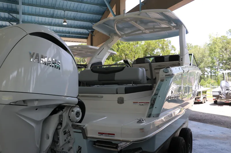 Slide: The Image of 2026 Chaparral 280 OSX boat with Yamaha engine, parked under a blue roof. - 4