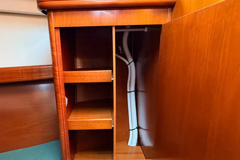Slide: The Image of Interior wooden cabinetry of a 2002 Beneteau 361 sailboat, featuring shelves and visible wiring. - 24