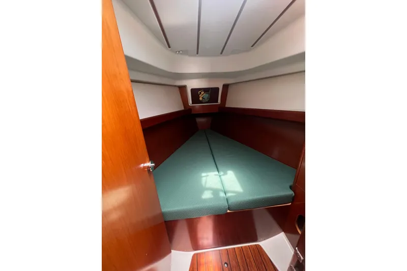 Slide: The Image of Cabin interior of 2002 Beneteau Oceanis 361 sailboat with green cushions and wooden finish. - 14