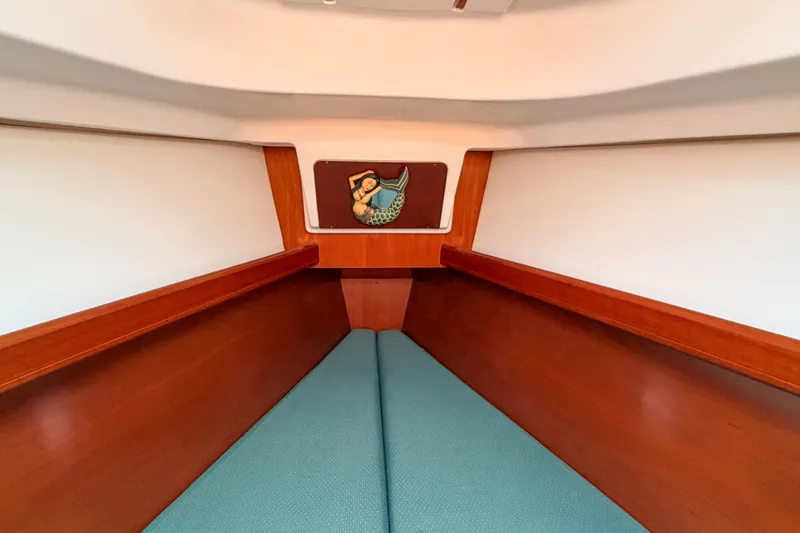 Slide: The Image of Interior of 2002 Beneteau 361 sailboat with wooden trim and teal cushions. - 19