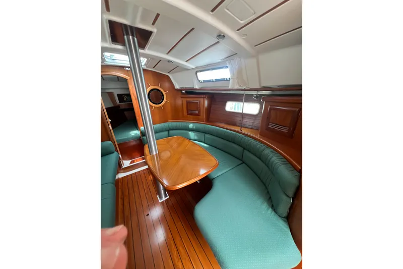 Slide: The Image of Interior of 2002 Beneteau Oceanis 361 sailboat with wooden table and green seating. - 9