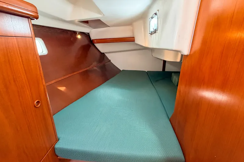 Slide: The Image of Cozy cabin interior of 2002 Beneteau 361 sailboat with wooden finish and green bedding. - 21
