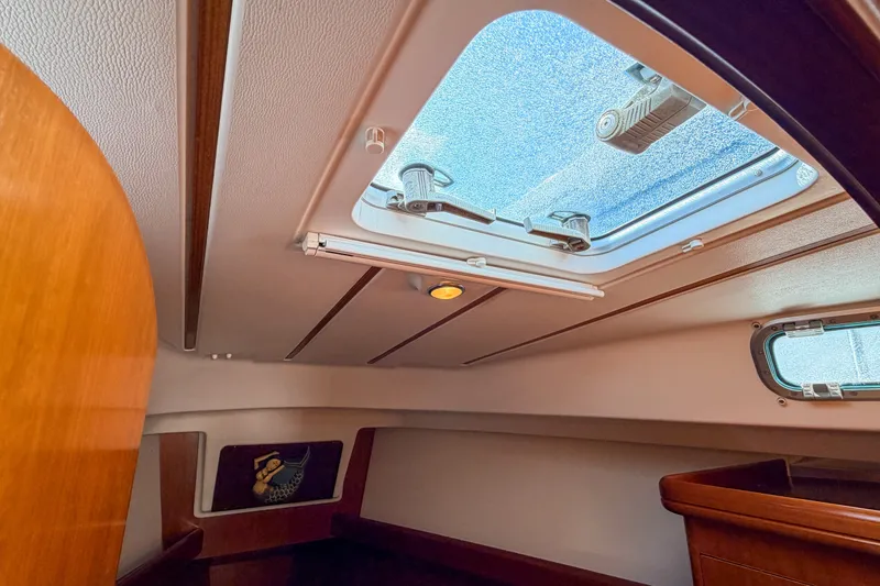 Slide: The Image of Interior cabin view of a 2002 Beneteau 361 sailboat, featuring a skylight and wooden finishes. - 22